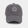 Detailed close-up of white smiley face embroidery on a charcoal grey cotton baseball cap - Gray