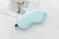 Pale blue silk eye mask with matching elastic strap, side view on white table - Jade Green