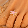 Adjustable golden toe ring featuring a pink enamel starfish on a sandy beach - Pink Starfish (S190)