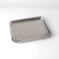 Close-up of a rectangular stainless steel grill pan with drainage holes for outdoor BBQ - Tray