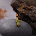 Detailed close-up of a gold-plated earring featuring a heart-shaped green gemstone - Natural Peridot Heart Pendant Gold