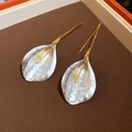 Macro detail of white pearl petal earrings with gold hooks on dark brown texture - Gold-Pearl White