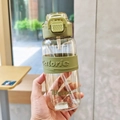 Detail of clear plastic water bottle with green silicone sleeve and built-in straw - Green