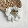 Polka dot fabric scrunchie in white and green on a rustic woven tray background - White with Green Dots