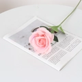 Artificial pink velvet rose with realistic green leaves on a minimalist white table - Round Silk Bean Paste
