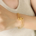 Minimalistisches Sicherheitsnadel-Armband in Gold am Handgelenk eines Models getragen - Überkreuztes Design Armreif (Z206-Gold)