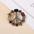 Spilla vintage segno della pace in lega dorata con strass colorati su sfondo minimalista - Simbolo della Pace con Strass