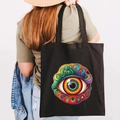 Black canvas tote bag with colorful graffiti Greek Evil Eye print on model shoulder - Design O-Psychedelic Eye-Black