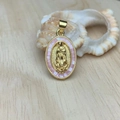 Close-up of golden oval Our Lady of Guadalupe pendant with pink shell inlay and zircon - Pink