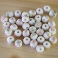 Macro shot of white ceramic beads with floral patterns on light wood background - No.47-Pink Purple Floral Leaf