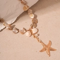 Detalle de collar de conchas con estrella de mar dorada, colgantes de caracol y perla - Collar de estrella de mar dorado