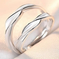Close-up of adjustable silver couple rings with twisted wave design on soft fabric - Male Style / Love For This Life