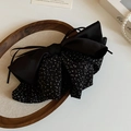 Detail eines eleganten schwarzen Haargummis mit Leopardenmuster auf einem Holztablett - Schwarze Gepunktete Schleife Haarklammer