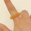 Detailaufnahme eines goldenen Spiralfingermassagerings mit flexibler Federstruktur - Gold