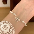 Detail of silver pearl bow bracelet on wrist with elegant lace cuff background - Silver Pearl Bow Fine Chain (MY31255)