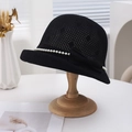 Detailed texture of black hollow knit bucket hat featuring white pearls and a bow - Black