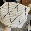 Close-up of beige knitted scarf with black diamond pattern and handmade label - Off-white