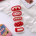Detailed view of five handcrafted knit hair clips with cherry and bow patterns on card - Red Set