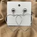 Detailed view of oversized hollow heart earrings on white card with golden satin background - Large Silver Heart