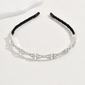Detailed view of silver crystal bow headband with black velvet tips on white surface - Bow (C7218)