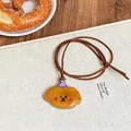 Mignon collier pendentif chien de dessin animé en résine sur table en bois - Chien Brun Avec Chapeau Violet