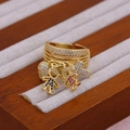Macro shot of 18K gold ring featuring zircon-encrusted heart, cross, boy and girl charms - Boy Girl
