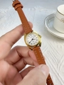 Detail of a women's gold quartz watch with a brown leather strap and Roman numerals - Brown Strap White Dial
