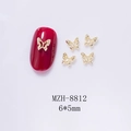 Macro detail of 6x5mm gold hollow butterfly nail charms on deep red nail tips - Gold Hollow Butterfly (8812)