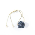 Detail of adjustable gold box chain bracelet with raw irregular black stone centerpiece - Obsidian