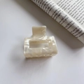 Dettaglio della pinza per capelli quadrata in acetato con texture marmo crema su rivista - Bianco