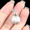 White turquoise wizard hat pendant with silver hook held between fingers - Howlite