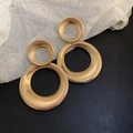 Macro detail of golden geometric double circle earrings with pleated metal texture - Gold Color (Steel Pin)