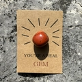 Macro view of a polished red crystal stone on a You're a Real Gem kraft paper gift card - Red Jasper