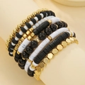 Detail of 7-piece layered bracelet set with white and gold clay beads on model's wrist - Black White Gold Combo