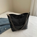 Glossy black leather shoulder bucket bag with gold chain strap shown on neutral background - Black