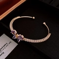 Gros plan d'un bracelet papillon doré avec zircons violets dans un écrin noir - Jonc Papillon Or Violet