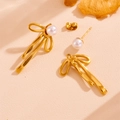Dettaglio di orecchini a fiocco dorato con perla e pendente rimovibile su beige - Orecchini a Lobo con Perle e Fiocco Oro (H211)