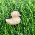 Carved natural stone duck with marble texture displayed on green artificial grass - Zebra