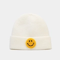 Detail van gebreide textuur van gebroken witte muts met gele smiley-patch op de omslag - Wit