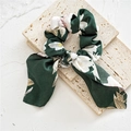 Dettaglio dello scrunchie in raso verde scuro a fiori con nastro lungo su lastre beige - Fiocco a Orecchio di Coniglio / Fiori Verdi