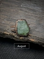 Macro shot of an irregular green peridot raw stone on a bronze vintage style ring band - August - Green Apatite