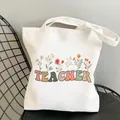 White canvas tote bag featuring TEACHER text and floral print on a black mesh chair - Style C8