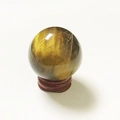 Tiger eye crystal sphere with natural golden-brown stripes on a small dark wooden stand - Tiger Eye Ball