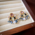 Detailed macro view of vintage earrings with colorful crystals and pearls on beige velvet - Gold Teardrop Wind Chime Studs