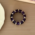 Vue de dessus d'un bracelet en résine violette avec maillons dorés sur fond de bois clair - Violet foncé