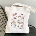 White canvas tote bag featuring pink cosmos flower print on a black iron chair - Pink Cosmos