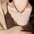 Close-up of golden sun pendant with white stone on brown cord necklace worn by model - Brown Cord Sun Starburst Pendant (2# Necklace-Gold-Coffee)