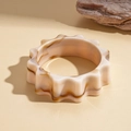 Nahaufnahme von marmoriertem Acryl-Armreif in Creme und Braun mit gewelltem Rand - Beige Marmor