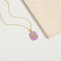 Macro view of purple enamel Hamsa Hand pendant with zircon inlay on a golden chain - Purple