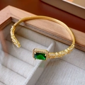 Primer plano de pulsera dorada con circón verde esmeralda y cristales en caja de regalo - Oro-Verde